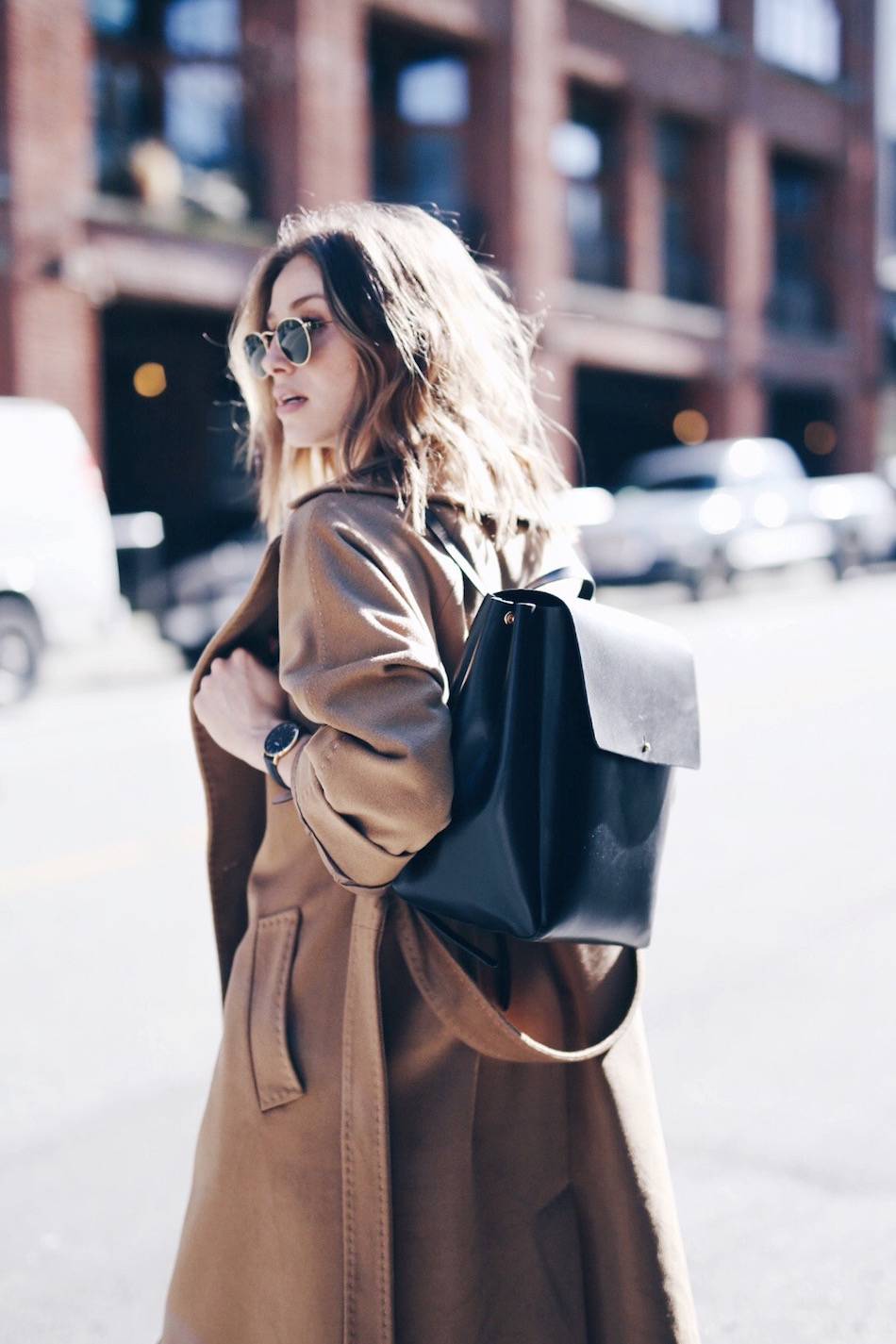 camel coat with black leather backpack