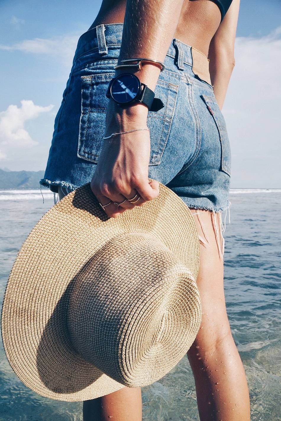 straw hat and vintage levi's shorts on beach with cluse marble watch