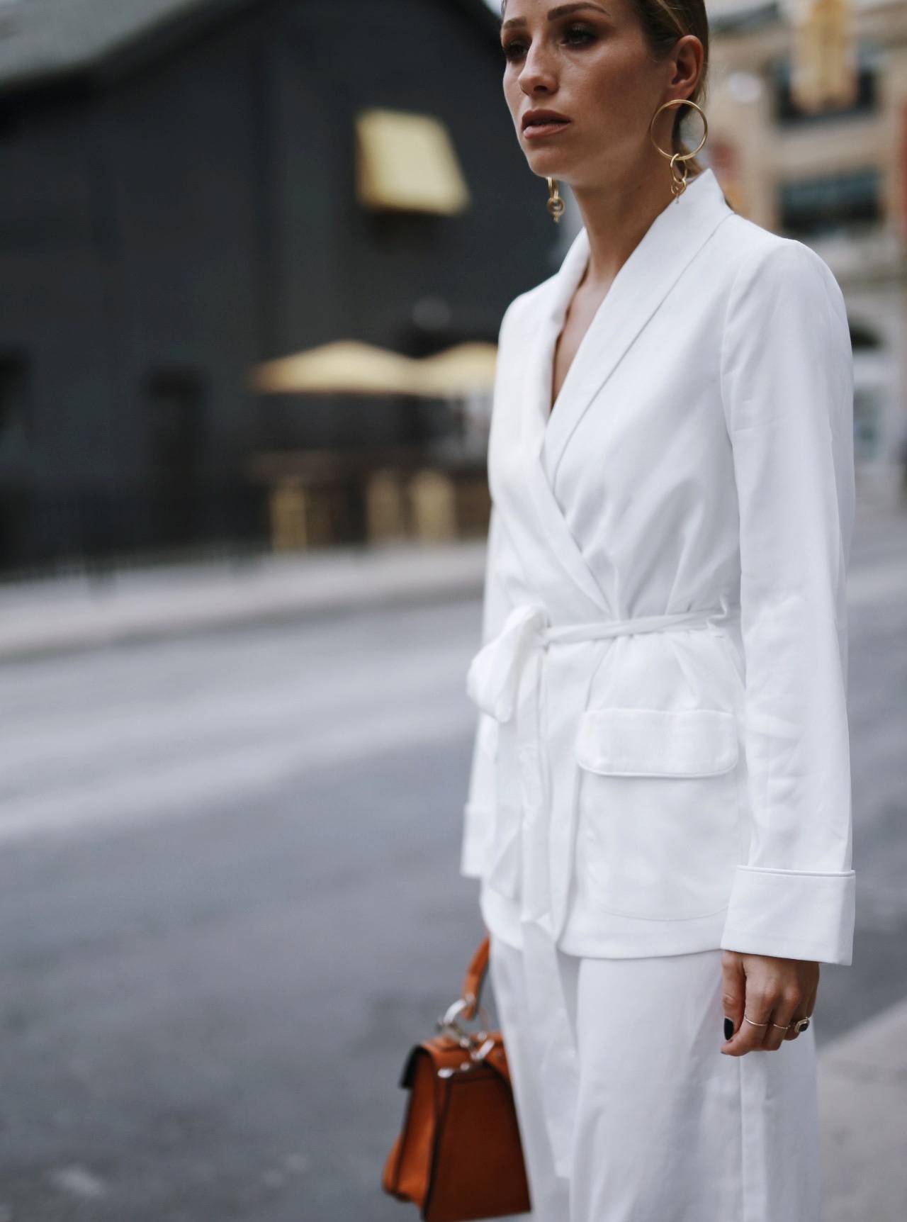Style and beauty blogger Jill Lansky of The August Diaries wearing a white silk suit, smokey eye, gold earrings, low ponytail 