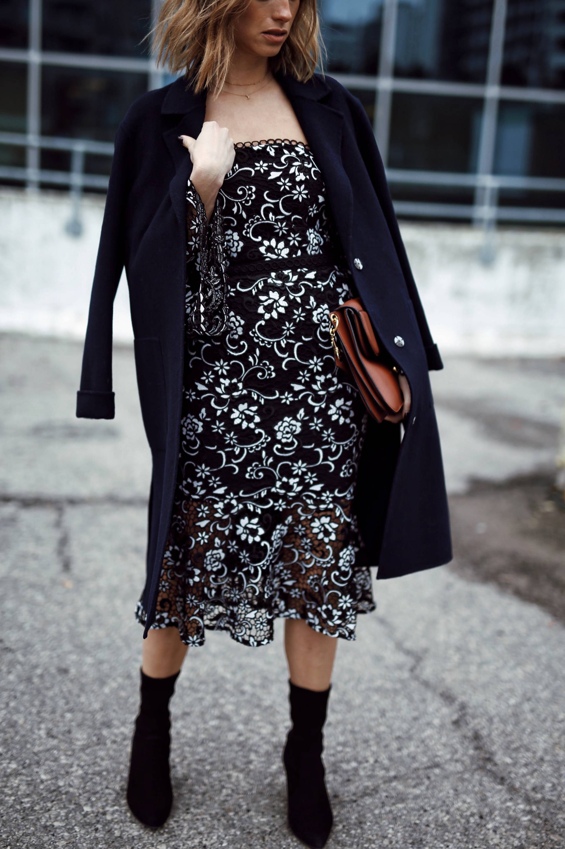 Style and beauty blogger Jill Lansky of the August Diaries in self portrait floral dress, navy coat over shoulders, stuart weitzman clinger booties