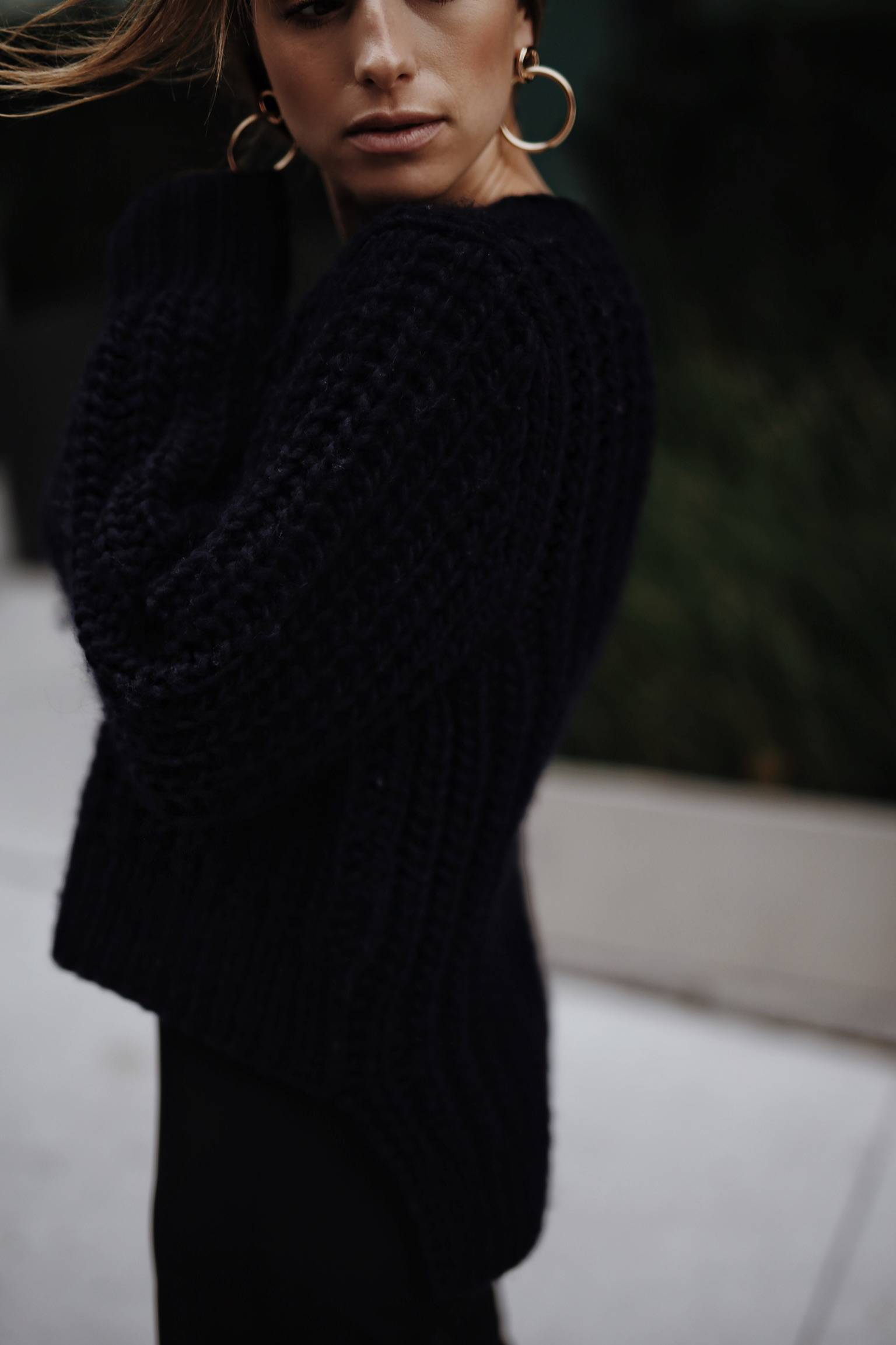 Style and beauty blogger Jill Lansky of The August Diaries shows how to wear black and navy together in a black slip dress and chunky navy knit and gold hoop earrings