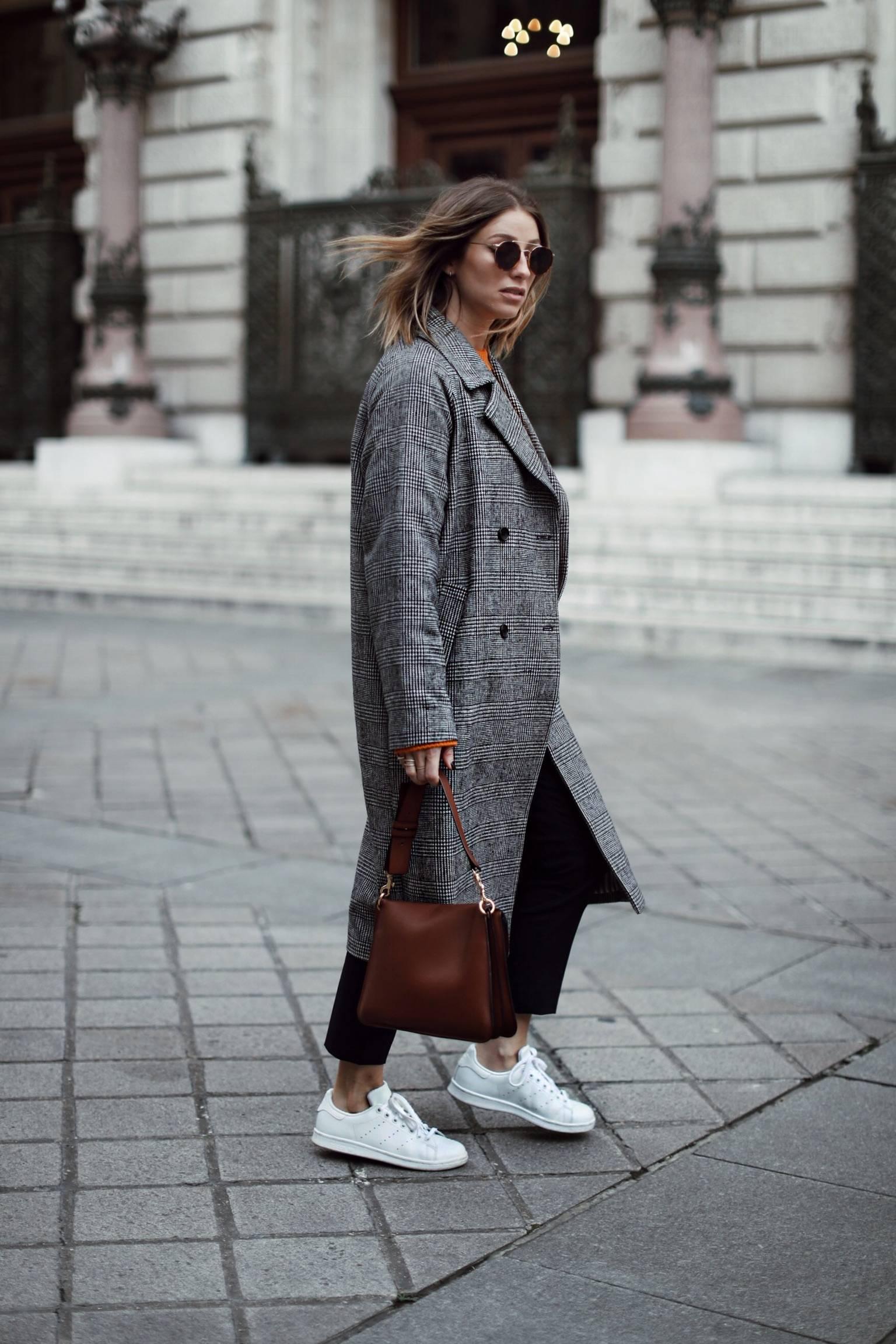 Style and beauty blogger Jill Lansky of The August Diaries on what to wear when traveling in plaid coat, sneakers, acne sweater